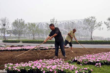 Two gardeners work in front of the National Stadium, nicknamed 'Bird's Nest', in Beijing, capital of China, June 20, 2008. A total of 40 million pots of flowers will be set at places including the Tian'anmen Square, Chang'an Street and all the Olympic venues in Beijing from June 20 to July 15. 