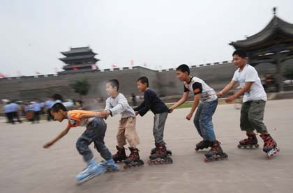Boys rollerskate in front of Yingxun Gate in Pingyao ancient city in North China's Shanxi Province, June 22, 2008. The Olympic flame will arrive at Pingyao on Wednesday. 