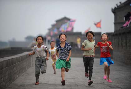 Four girls run on the ancient city walls of Pingyao in North China's Shanxi Province June 22, 2008. The Olympic flame will arrive at Pingyao on Wednesday. 