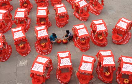 Women prepare lantern costumes in front of Yingxun Gate in Pingyao ancient city in North China's Shanxi Province, June 22, 2008. The Olympic flame will arrive at Pingyao on Wednesday.