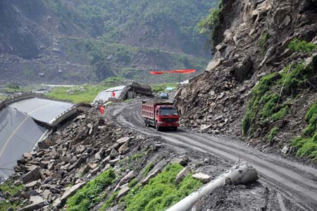 An engineering vehicle passes the temporary line of the No. 213 national highway connecting Dujiangyan City and Wenchuan County in southwest China's Sichuan Province, June 17, 2008. Some 43.3 kilometers of the national and provincial highways still remain to be repaired after the Wenchuan earthquake. 