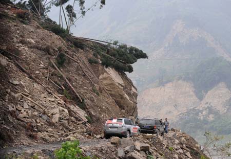 Two vehicles park on the No. 317 national highway as the road is blocked by fallen rocks due to the landslide caused by the earthquake in Yingxiu Township, Wenchuan County, southwest China's Sichuan Province, June 17, 2008. Some 43.3 kilometers of the national and provincial highways still remain to be repaired after the Wenchuan earthquake.