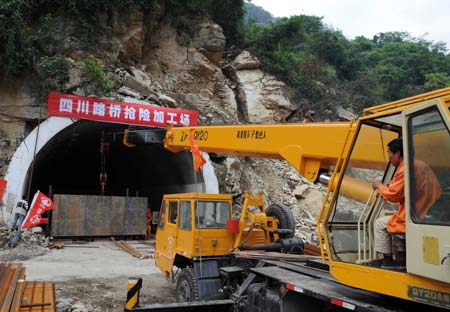 An engineering vehicle works at the gate of a tunnel connecting the No. 213 and the No. 317 national highways in Yingxiu Township, Wenchuan County, southwest China's Sichuan Province, June 17, 2008. Some 43.3 kilometers of the national and provincial highways still remain to be repaired after the Wenchuan earthquake.