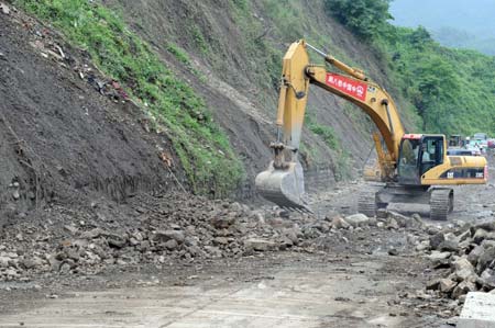 An engineering vehicle works to repair the road connecting Yinghua Township and Hongbai Township in Shifang City, southwest China's Sichuan Province, June 19, 2008. Some 43.3 kilometers of the national and provincial highways still remain to be repaired after the Wenchuan earthquake.