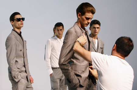 A worker adjusts a model's clothes as he displays a creation from Gianfranco Ferre' Spring/Summer 2009 men's collection during Milan Fashion Week June 22, 2008.