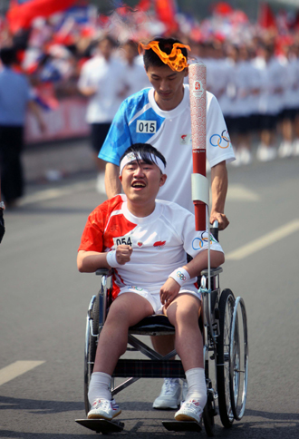 Torchbearer Yan Jiang, a wheelchair user, cheers during the Beijing Olympic torch relay in Taiyuan, Shanxi Province, June 26, 2008.