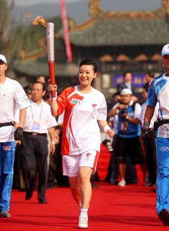Torchbearer Tan Jing smiles as she runs with the Beijing Olympic torch during its relay in Taiyuan, Shanxi Province, June 26, 2008.