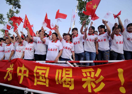 Spectators wave flags to welcome the torch during the Torch Relay in Taiyuan city, Shanxi province, on June 26.