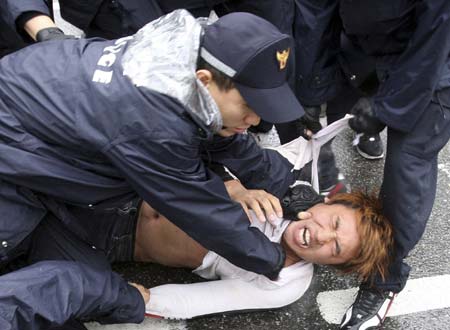 Policemen detain a protester after an overnight candle-light rally demanding a full-scale renegotiation of the beef deal with the U.S. and the resignation of President Lee Myung-bak on the road leading to the U.S. embassy and the presidential Blue House in Seoul June 22, 2008. South Korea, which reworked an unpopular U.S. beef import deal that sparked mass street protests, could soon resume imports once a legal step has been completed, the trade minister said on Saturday, while tens of thousands of people fearing infection of mad cow disease held the anti-government rally. 