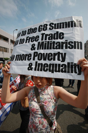 An anti-G8 protester holds a placard during a rally in Kyoto, western Japan, on June 26, 2008, prior to the two-day G8 Foreign Ministers' Meeting to be held in this city from June 26 to 27.