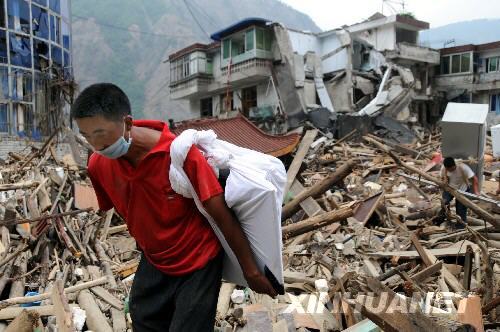 The photo taken on June 20 shows two men carry their belongings from the quake-hit Beichuan County.