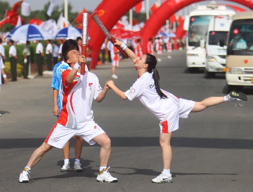 Photo: Torchbearer Ma Junting lights the torch for the next torchbearer Ma Zhifang 