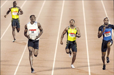 World record holder Usain Bolt (second left) looks over at Asafa Powell (right) as he wins the 100 meters final at the Jamaican trials for the Beijing Olympics in Kingston on Saturday.