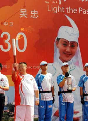 Torchbearer Huo Qinghua stands at the lauching ceremony with torch during the 2008 Beijing Olympic Games torch relay in Wuzhong City of northwest China's Ningxia Hui Autonomous Region June 30, 2008.