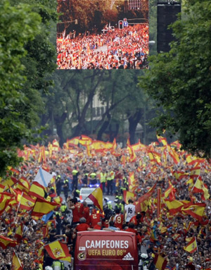 Spain's Euro 2008 soccer players celebrate on the top of a bus surrounded by a cheering crowd as they arrive at Madrid's Colon square, June 30, 2008.(Xinhua/Reuters Photo)