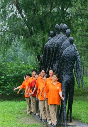  People pose for group photos in front of a set of sculptures at Beijing Olympics Forest Park in Beijing, capital of China, July 1, 2008. 