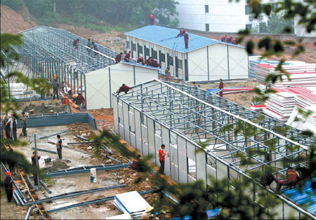 Construction workers build temporary houses for quake victims last month, in Mianyang, Sichuan province. [File Photo: China Daily]