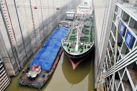  The flotilla of a super marine Tianbao 01 oil tanker sails through the dual-passage and five-step navigation lock of the Three Gorges Project in Yichang City, central China's Hubei Province, July 1, 2008. The 24.2-meter high Tianbao 01 oil tanker, a China-made new vessel for the order from Greece, is dragged by tugboat (L) to waltz through the Three Gorges Dam and Gezhouba Dam under the multiple water levels control methods by the Three Gorges Navigational Bureau.