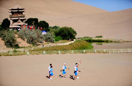  Torchbearer He Ting (1st R) runs during the 2008 Beijing Olympic Games torch relay near the Yueyaquan Lake in Dunhuang, a city of northwest China&apos;s Gansu Province, on July 5, 2008.