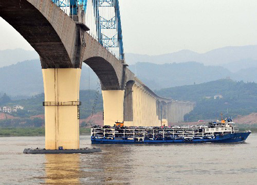 A boat drives past the Yichang-Wanzhou Yangtze River bridge, which has been installed with a set of floating bump-shielding apparatus on Thursday, July 3, 2008. The bridge is located in Yichang in central China's Hubei Province. [Photo: Xinhua]