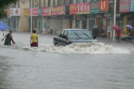 People walk and the vehicle moves on the flooded Weiming Road in Cangzhou City, north China's Hebei Province, July 5, 2008. Heavy rainfall hit Cangzhou on Saturday. (Xinhua/Fu Xinchun)
