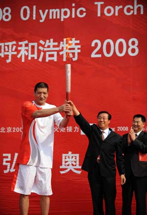 Menk Bateer (L), the first torchbearer, receives the torch from Han Zhiran, secretary of the Hohhot City Committee of the Communist Party of China, during the 2008 Beijing Olympic Games torch relay in Hohhot, capital of north China's Inner Mongolia Autonomous Region, on July 8, 2008.