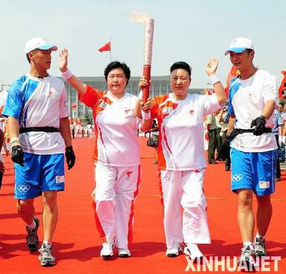 Long Mei (R) and Yu Rong carry the Olympic torch in Baotou, Inner Mongolia Autonomous Region July 9. 