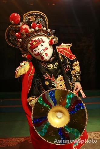 Liu Shihu, a Sichuan opera performer, demonstrates his face-changing skills with a mask featuring the Fuwa Huanhuan, one of the five Beijing Olympic mascots, in Suining, SichuanJuly 7, 2008. Face changing, or 'bianlian' in Chinese is a stunt where performers change masks in the blink of an eye in Sichuan opera. [Asianewsphoto] 