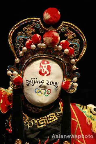 Liu Shihu, a Sichuan opera performer, demonstrates his face-changing skills with a mask featuring the Beijing 2008 Olympic emblem in Suining, Sichuan July 7, 2008. Face-changing, or 'bianlian' in Chinese is a stunt where performers change masks in the blink of an eye in Sichuan opera. [Asianewsphoto] 
