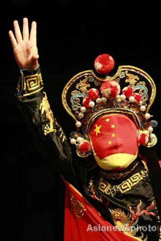 Liu Shihu, a Sichuan opera performer, demonstrates his face-changing skills with a mask featuring the Chinese national flag in Suining, Sichuan July 7, 2008. Face-changing, or 'bianlian' in Chinese is a stunt where performers change masks in the blink of an eye in Sichuan opera. [Asianewsphoto] 