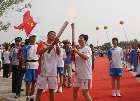 The first torchbearer Su Rina passes the Olympic flame to the second torchbearer in Chifeng city, Inner Mongolia Autonomous Region, on July 10.