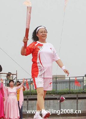 Torchbearer Siqingaowa, a renowned actress, carries the Olympic torch in Chifeng city, Inner Mongolia Autonomous Region, on July 10.
