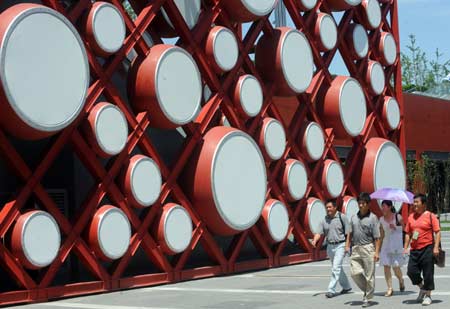 Visitors walk past a grid wall with drums inlaid at the man-made sinkage square in the Olympic Forest Park in Beijing, capital of China, July 6, 2008. 