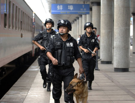 Three special policemen of Bengbu Railway Special Police Detachment patrol the Bengbu Railway Station platform with a police dog. In order to ensure Olympic security, the Bengbu railway policemen in Anhui Province are on patrol everyday to check suspicious goods or activities.