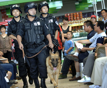 Policemen from the Bengbu Railway Special Police Detachment patrol the waiting hall of Bengbu Railway Station in East China's Anhui Province with a police dog, July 10, 2008. In order to ensure Olympic security, the Bengbu railway policemen are on patrol everyday with police dogs to check for suspicious goods and activities. 