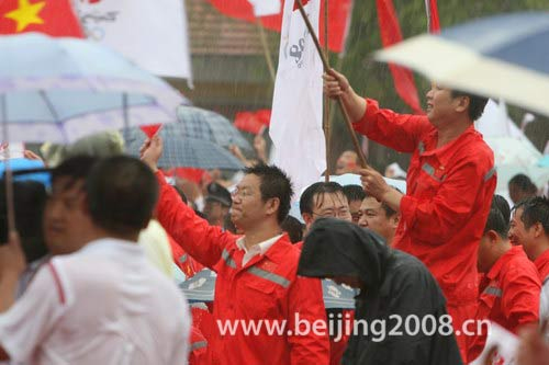 People welcome the Olympic torch in rain in Daqing, Heilongjiang province, on July 12, 2008. 