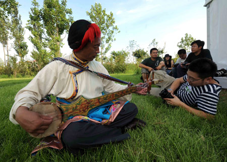 Tibetan artist Soinam plays a Tibetan song in front of a "Lucky Cloud House" in Beijing, China, July 13, 2008. A cultural exhibition themed "China Story" is to open from Aug. 9 to 24 and Sept. 7 to 17 to exhibit outstanding representations of ethnic culture and folk art of China in the "Lucky Cloud Houses." Images, objects and multimedia works of art, as well as handicrafts performances from all over China will be displayed in the exhibition. 