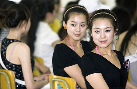 Twin sisters, Li Xiaoye(left) and Li Ziye, from Civil Aviation Management Institute of China, behave at the opening ceremony for the training of Olympic volunteers.