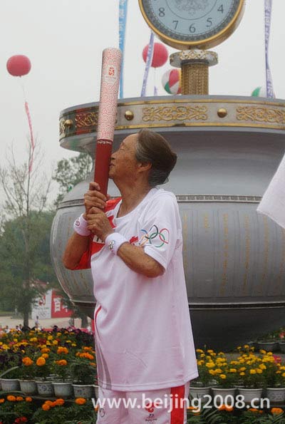 The last torchbearer Bai Qing kisses the torch during the Torch Relay in Songyuan, Jilin province, on July 15.