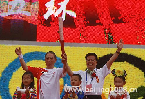 The first torchbearer Li Shu receives the torch from local official during the Torch Relay in Songyuan, Jilin province, on July 15.