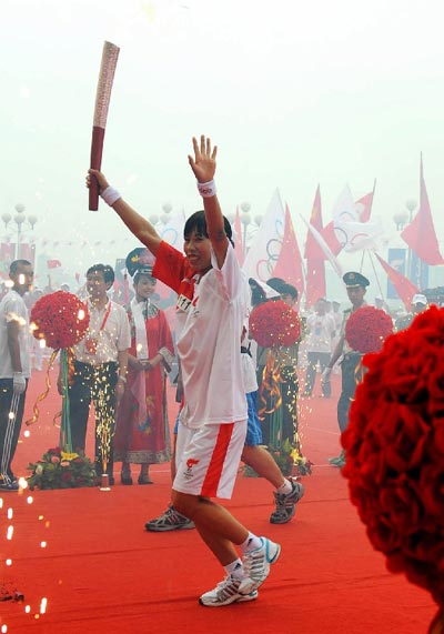 The first torchbearer Wang Chunli carries the torch during the Torch Relay in Jilin, Jilin province, on July 15.