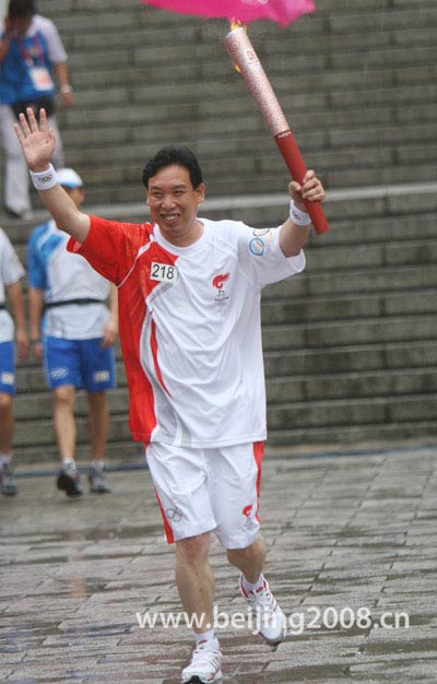The last torchbearer Wang Jinjun waves to the spectators during the torch relay in Jilin City, northeast China's Jilin Province, on July 15, 2008.