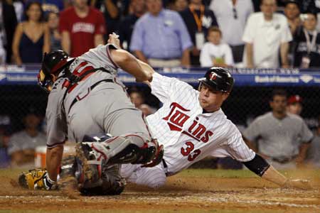 Minnesota Twins Justin Morneau (R) scores the game-winning run from third on a sacrifice fly in the 15th inning as Atlanta Braves catcher Brian McCann tries to make the tag during Major League Baseball's All-Star game at Yankee Stadium in New York July 15, 2008.