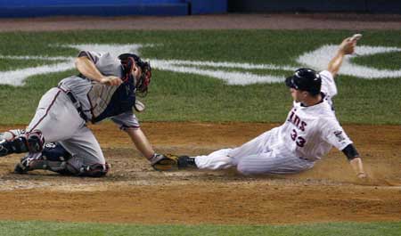 Minnesota Twins Justin Morneau (R) scores the game-winning run from third on a sacrifice fly in the 15th inning, as Atlanta Braves catcher Brian McCann tries to make the tag, during Major League Baseball's All-Star game at Yankee Stadium in New York July 15, 2008.