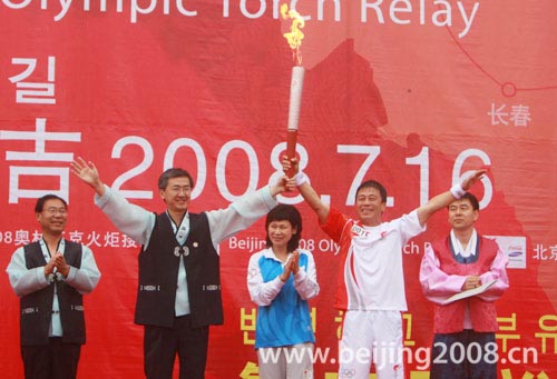 Deng Kai (L) and Jin Guangzhen carry the torch together during the torch relay in Yanji, Jilin Province, on July 16, 2008. 