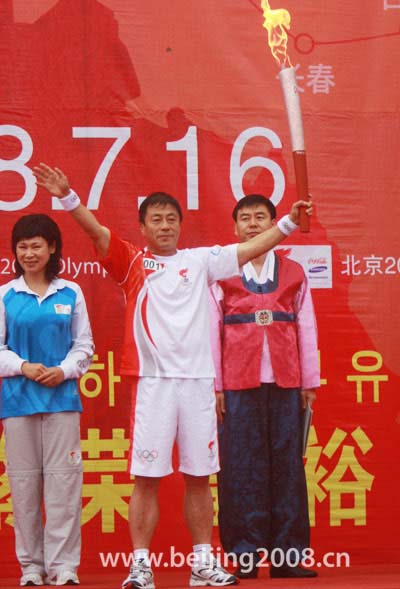 The first torchbearer holds up the torch during the Torch relay in Yanji, Jilin Province, on July 16, 2008. 