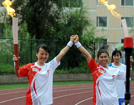 Torchbearers strike a pose after passing the flame during the Torch relay in Yanji, Jilin Province, on July 16, 2008.