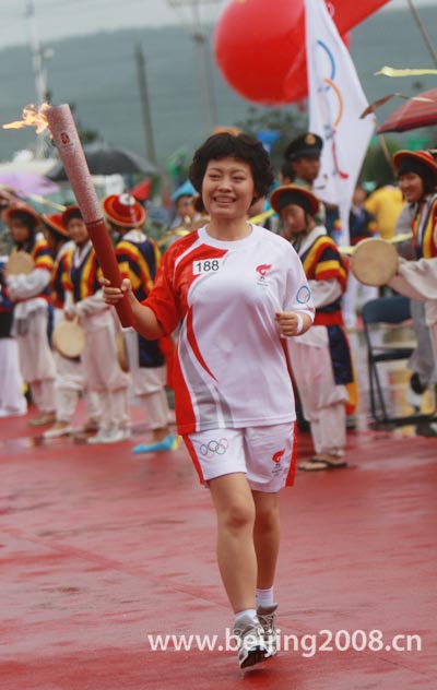 Last torchbearer Xie Jun runs with the torch in rain during the Torch relay in Yanji, Jilin Province, on July 16, 2008.