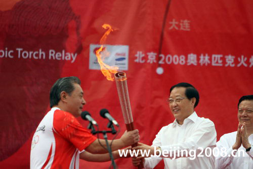 The first torchbearer Liu Hongtu receives the torch from the official during the torch relay in Shenyang, Liaoning Province, on July 17, 2008.