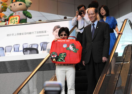 The first Hong Kong resident (front) to buy the special-edition HK$20 Olympic banknote leaves Bank of China in Central, Hong Kong, July 16, 2008. Four million banknotes have been officially issued in Hong Kong, Macao and some overseas regions. There are three categories of banknotes: a single bill, a set of four and a set of 35. 